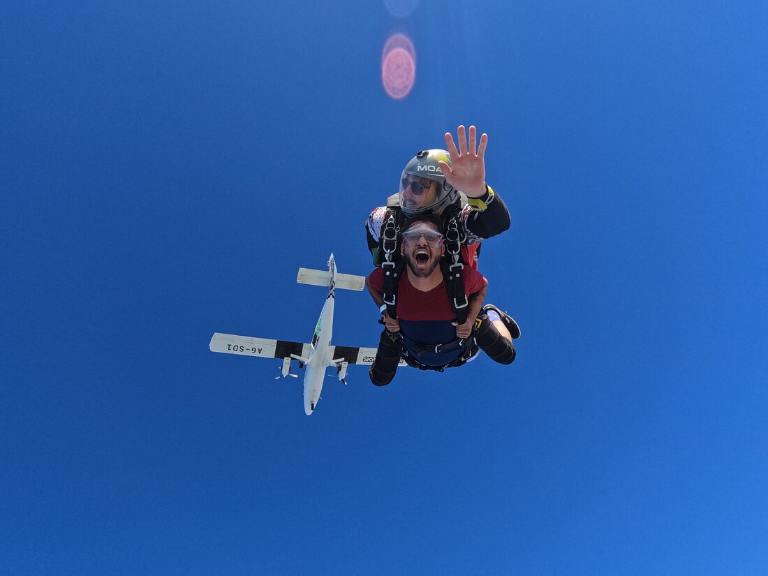 Bhavik Sarkhedi skydiving, waving beneath the plane